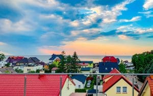 Widok z tarasu na kolorowe dachy Sarbinowa i Morze Bałtyckie o zachodzie słońca