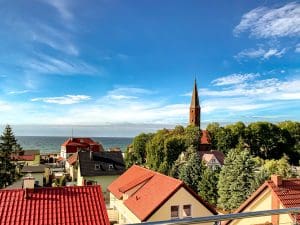 Letnia panorama Sarbinowa z wieżą kościoła i morzem w tle