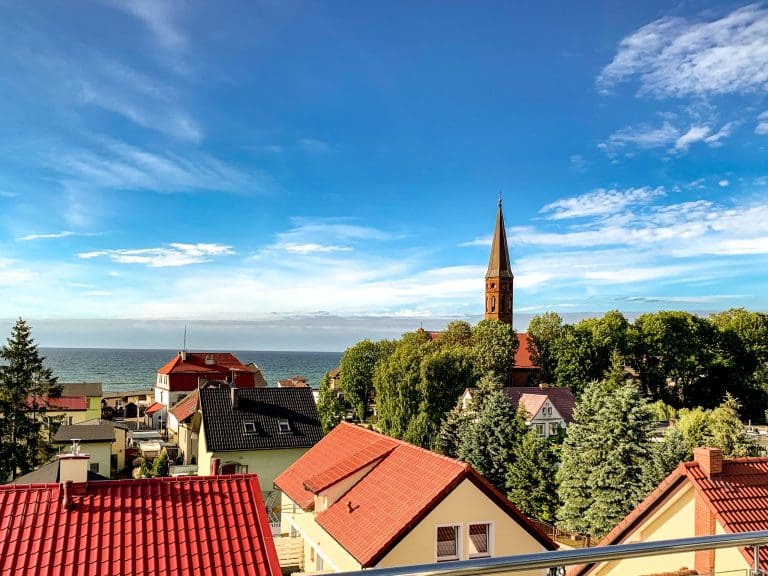 Letnia panorama Sarbinowa z wieżą kościoła i morzem w tle
