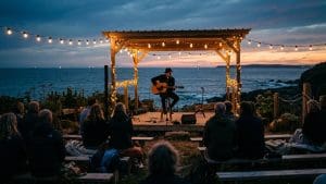 Gitarzysta na plenerowej scenie z lampkami nad wodą wieczorem