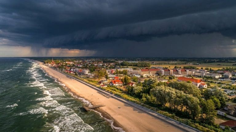 Ciemny wał chmur burzowych nad plażą i zabudową Sarbinowa, widok z lotu ptaka