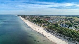 Szeroka plaża w Sarbinowie z turkusową wodą i falochronami, widok z drona