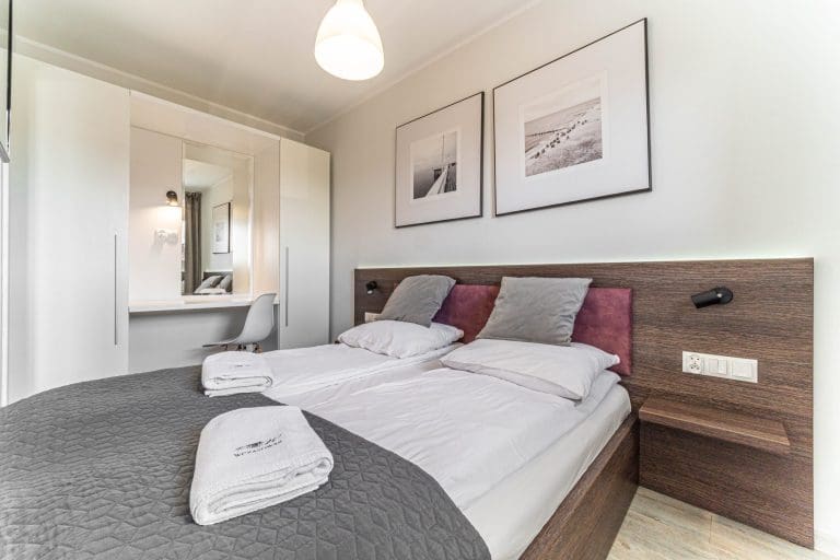 Sypialnia w apartamencie z zaścielonym łóżkiem i złożonymi ręcznikami.