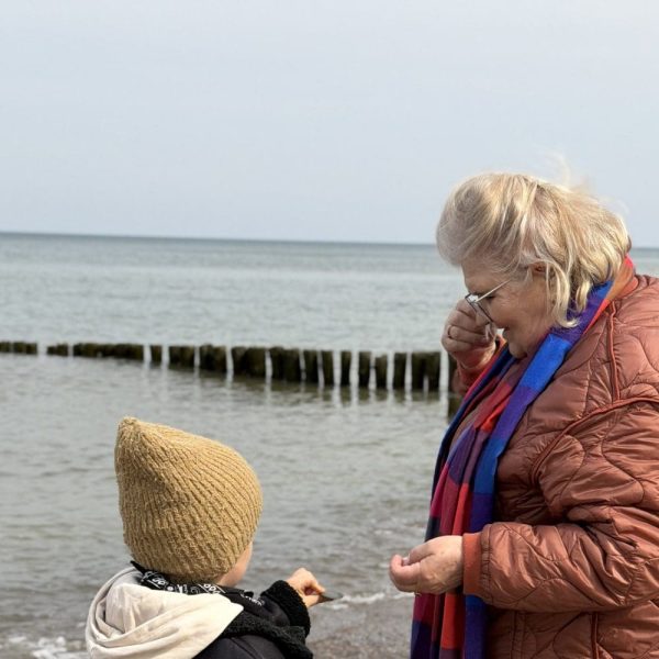 Babcia z wnukiem oglądają kamyki na brzegu morza