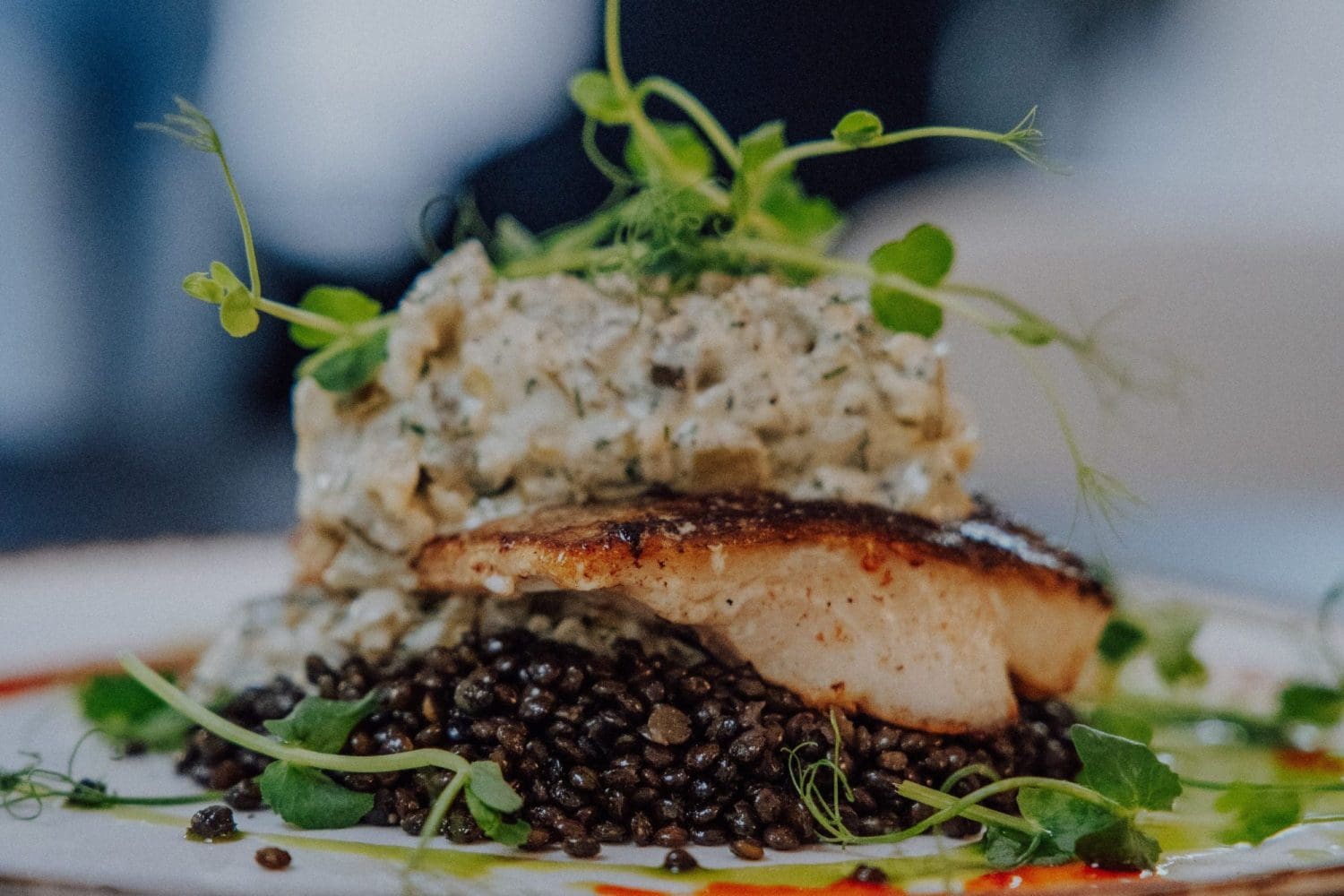 Smażony filet z ryby na czarnej soczewicy z ziołami, danie z restauracji Dobre Smaki