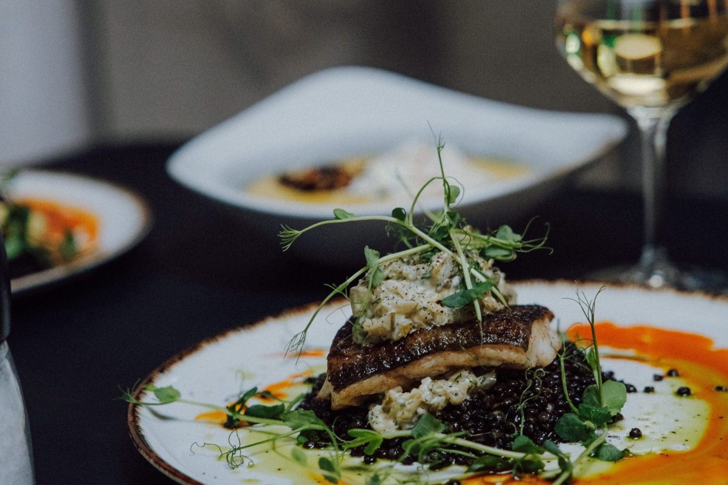 Smażona ryba z dodatkami i kieliszek białego wina na stole w restauracji Dobre Smaki