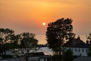 Słońce nisko nad morzem widziane z tarasu nad dachami Sarbinowa