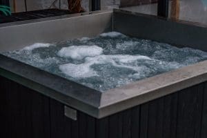 Jacuzzi z ciemną obudową, woda bąbelkuje od hydromasażu.