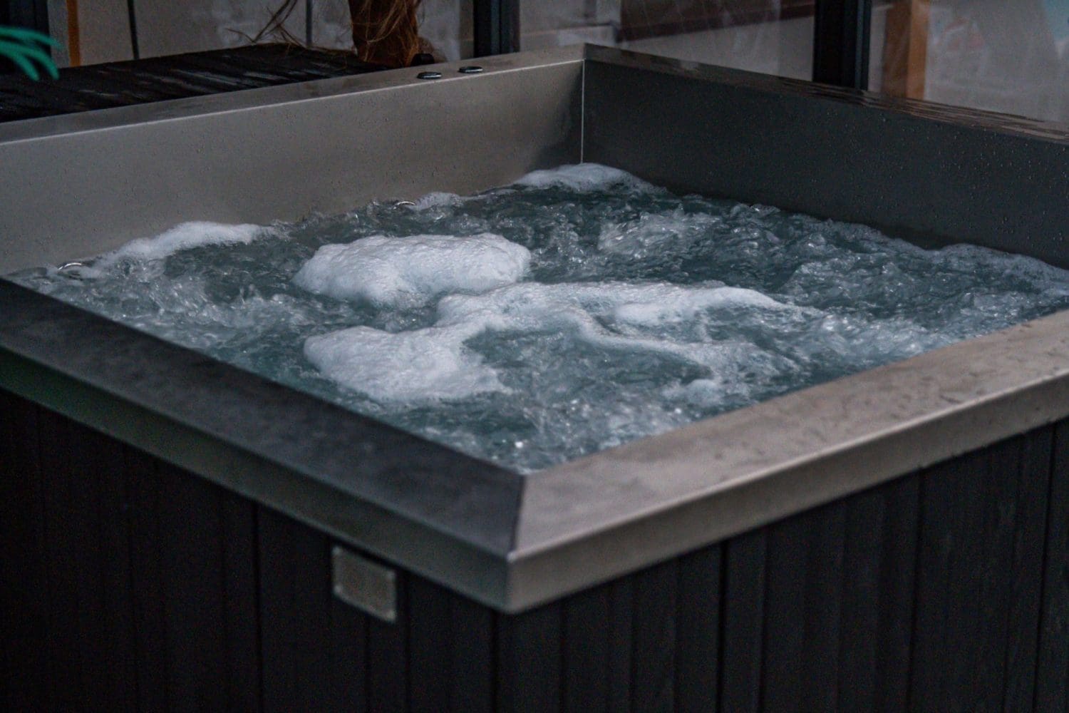 Jacuzzi z ciemną obudową, woda bąbelkuje od hydromasażu.