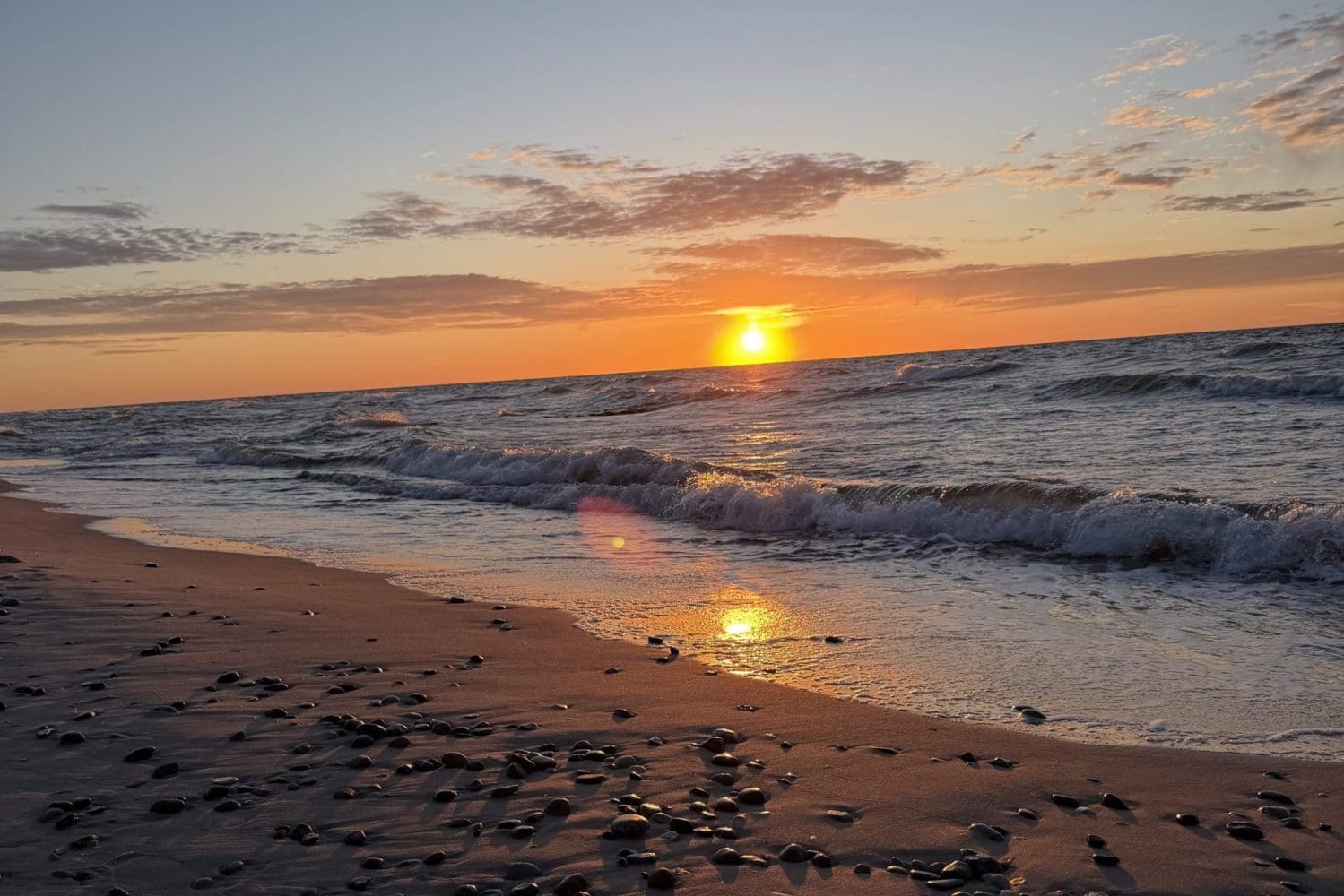 Zachód słońca nad Bałtykiem widziany z plaży w Sarbinowie, ciemny piasek na pierwszym planie