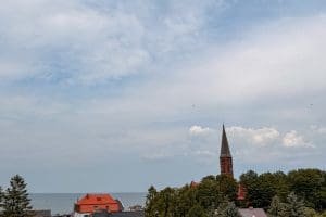 Wysokie chmury nad wieżą kościoła w Sarbinowie i morzem w tle