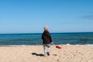 Dziecko z czerwoną łopatką na pustej plaży w Sarbinowie