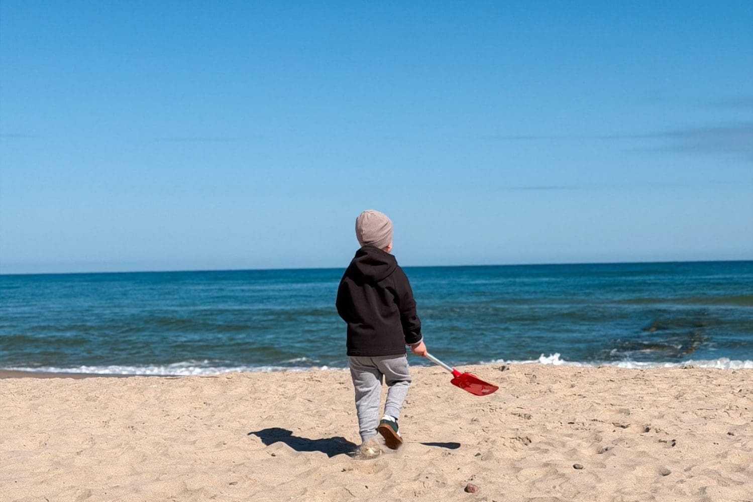 Dziecko z czerwoną łopatką na pustej plaży w Sarbinowie