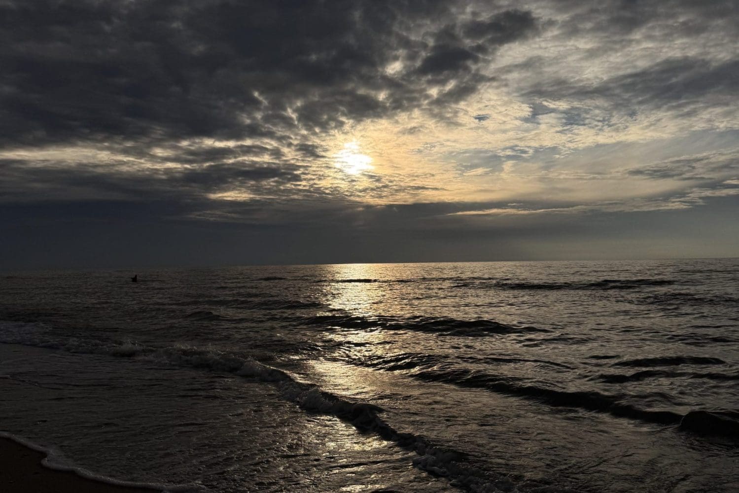 Zachmurzone niebo nad Bałtykiem i szara, wzburzona woda przy brzegu w Sarbinowie