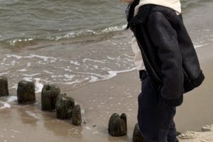 Drewniane pale falochronu przy brzegu i mokry piasek na plaży w Sarbinowie