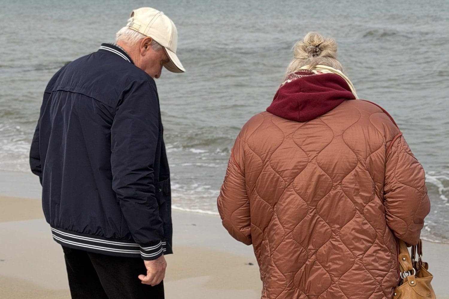 Para seniorów idąca plażą w Sarbinowie pod zachmurzonym niebem