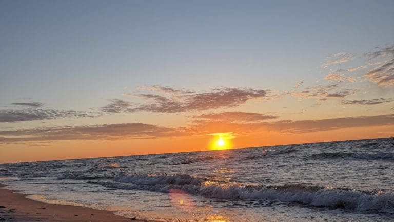 Słońce nisko nad horyzontem Bałtyku i pusta plaża w Sarbinowie
