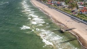 Plaża w Sarbinowie z lotu ptaka: linia brzegu Bałtyku, drewniany pomost i pojedynczy spacerowicze