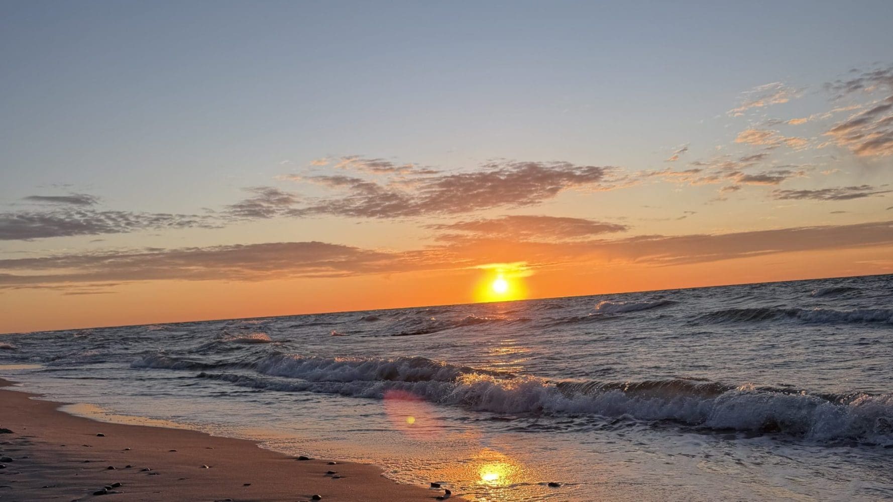 Pusta plaża w Sarbinowie o zachodzie słońca, fale Bałtyku rozbijające się o brzeg