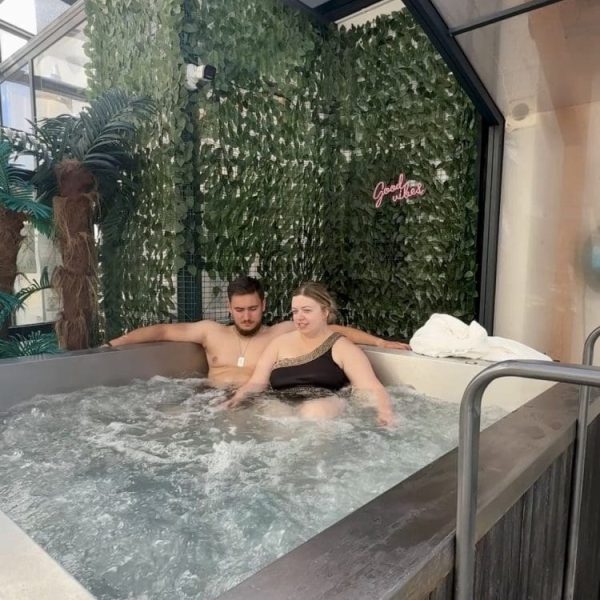 Para odpoczywa w bulgoczącym jacuzzi pod przeszklonym dachem strefy basenowej