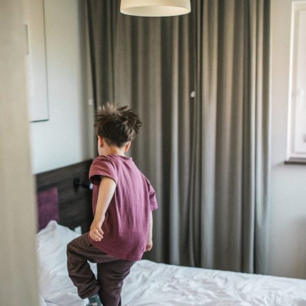 Chłopiec skacze na łóżku w apartamencie o poranku
