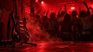 Gitara elektryczna na statywie w smudze dymu w czerwonym świetle klubu, w tle publiczność od tyłu