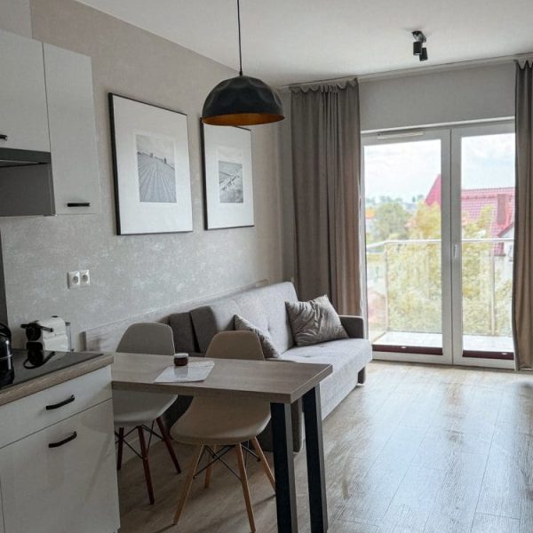 Jasny apartament z aneksem kuchennym, stołem i wyjściem na balkon