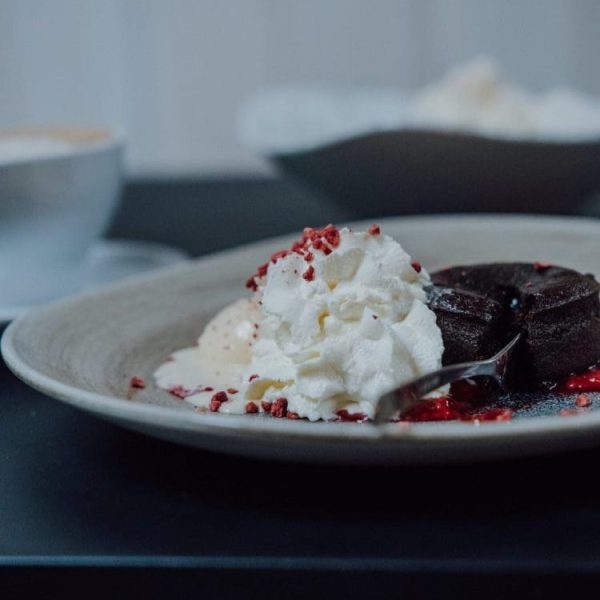 Czekoladowy lava cake z bitą śmietaną i liofilizowanymi malinami