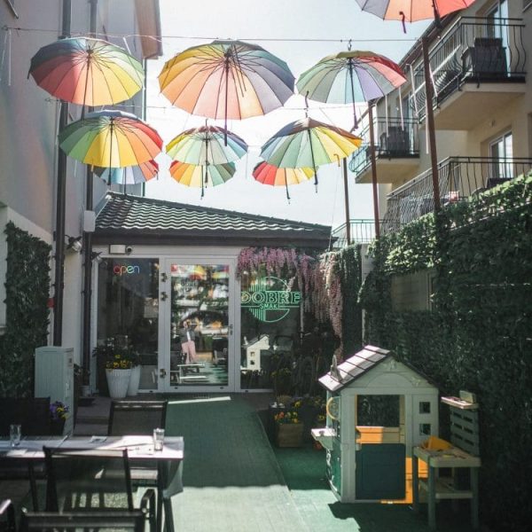 Ogródek restauracji Dobre Smaki z kolorowymi parasolami i domkiem dla dzieci