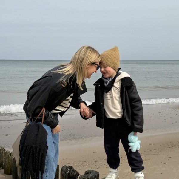 Mama i synek w kurtkach na plaży przy drewnianych palach